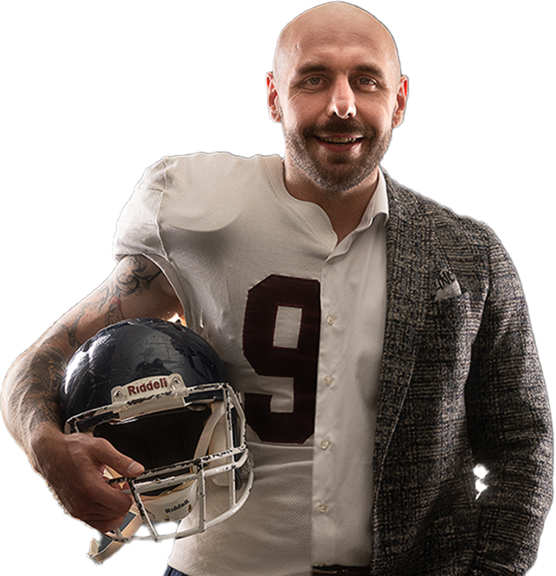 Peter Maier im Footballtrikot mit Helm unter dem Arm und Sakko über der Schulter